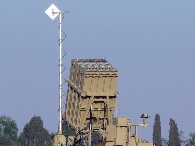 A mast-mounted antenna beside a command and control array — the antenna is the radiating asset that needs protecting