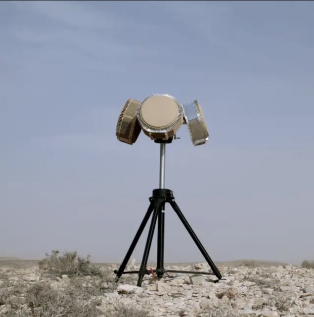 A tripod-mounted multi-panel tactical radar array in open desert terrain