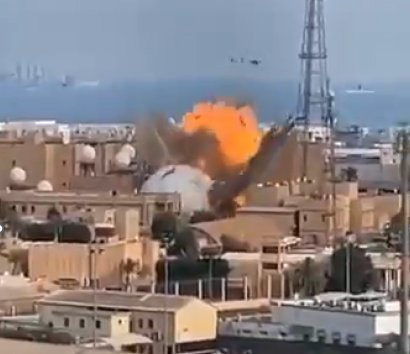 An explosive strike hitting a radome next to a communications tower on a coastline